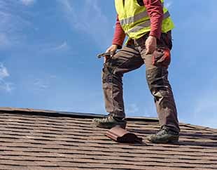 South Creek Roofing & Waterproofing Inc. Roofing Services - Contractor on top of roofing looking giving roof inspection